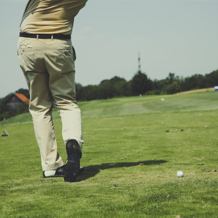 Golfer at the moment of a swing on a green fairway under a clear sky